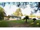 View of the home featuring a front yard with palm trees, and attached carport on a sunny day at 19455 Fort Dade Ave, Brooksville, FL 34601