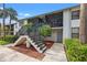 Condo building with white exterior, stairs, and beautiful landscaping with palms leading to a screened in porch at 1986 Pelican Landing Blvd # 1514, Clearwater, FL 33762