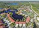 Aerial view of a planned community with lake, fountain, tennis courts, and clusters of red-roofed townhomes at 21205 Calle Rosa Dr # 10, Land O Lakes, FL 34637