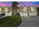 Townhome exterior featuring manicured front lawn, palm tree, and white garages and balconies under a dusky sky at 21205 Calle Rosa Dr # 10, Land O Lakes, FL 34637