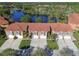 Aerial view of townhomes with tile roofs, garages, and landscaping, set by a lake and lush trees at 21205 Calle Rosa Dr # 10, Land O Lakes, FL 34637