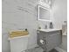 Modern powder room featuring gray vanity, illuminated mirror, and white marble wall at 21205 Calle Rosa Dr # 10, Land O Lakes, FL 34637