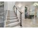 Illuminated staircase with wood-look floors leads to an open floor plan with kitchen island and black stainless appliances at 21205 Calle Rosa Dr # 10, Land O Lakes, FL 34637