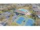 Aerial view of community tennis courts and pool area surrounded by palm trees at 2514 Sandy Hill Ct, Holiday, FL 34691