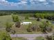 Aerial view of a country home surrounded by lush pastures, scattered trees, and open green space at 39745 River Rd, Dade City, FL 33525