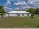 Charming one-story home with a metal roof, lush green lawn, and manicured landscaping at 39745 River Rd, Dade City, FL 33525