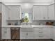 Bright kitchen featuring white cabinetry, farmhouse sink, stainless dishwasher, and elegant countertops at 39745 River Rd, Dade City, FL 33525