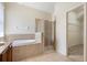 Bathroom featuring a large soaking tub, a glass-enclosed shower, and a view into the walk-in closet at 4515 Fieldview Cir, Wesley Chapel, FL 33545