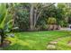 Sprawling backyard with healthy lawn, brick pathway, tropical plants, and bench seating at 54 Aegean Ave, Tampa, FL 33606