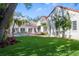 Spacious backyard features lush lawn, patio, tropical foliage, and a home with a red tile roof at 54 Aegean Ave, Tampa, FL 33606