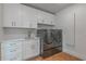 Well-lit laundry room with white cabinets, granite countertops, and modern washer and dryer units at 54 Aegean Ave, Tampa, FL 33606