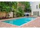 Backyard pool featuring brick patio, lush tropical landscaping, and outdoor grill area at 54 Aegean Ave, Tampa, FL 33606