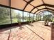 Enclosed sunroom with brick flooring and peaceful views of the surrounding pond and landscaping at 5702 War Admiral Dr, Wesley Chapel, FL 33544