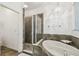Bright bathroom with a glass-enclosed shower, a soaking tub, and stylish chandelier at 6239 French Creek Ct, Ellenton, FL 34222