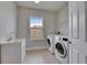Well-equipped laundry room includes a utility sink, modern washer and dryer, and tile flooring for efficient chores at 6423 Seasound Dr, Apollo Beach, FL 33572