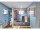 Blue bathroom with marble look shower, wood-look floors, and small windows at 6501 62Nd N St, Pinellas Park, FL 33781