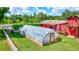 Exterior view of a greenhouse and a barn with trees in the background at 6501 62Nd N St, Pinellas Park, FL 33781