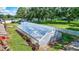 Exterior view of transparent greenhouse with white frame sits on green grass with trees in background at 6501 62Nd N St, Pinellas Park, FL 33781