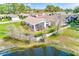 Home with a screened-in porch offering serene views of a pond, surrounded by lush landscaping and greenery at 9426 Green Needle Dr, New Port Richey, FL 34655