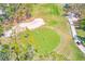 Aerial view of golfers on a green with sand traps and a golf cart on the cart path at 9426 Green Needle Dr, New Port Richey, FL 34655