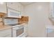 The kitchen features white appliances, tiled backsplash, and white cabinets with a washer/dryer combo at 1012 Pearce Dr # 105, Clearwater, FL 33764