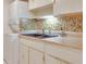 A kitchen sink featuring a double basin sink, tiled backsplash, and white cabinets, paired with a washer/dryer combo at 1012 Pearce Dr # 105, Clearwater, FL 33764