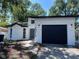 Charming home featuring a black garage door, white stucco, and modern exterior lighting fixtures at 10216 N Pawnee Ave, Tampa, FL 33617
