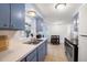 Cozy kitchen features blue cabinets, stainless steel appliances, double sink, and a pass-through window at 10900 Oakdale Ave, Port Richey, FL 34668