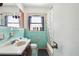 Retro turquoise-tiled bathroom featuring a vanity, toilet, and shower-tub combination at 1407 Overlea St, Clearwater, FL 33755