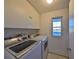 Well-lit laundry room with washer, dryer, and storage cabinets at 1507 Hartwick Dr, Sun City Center, FL 33573