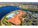 Stunning aerial view of the community clubhouse, featuring a large pool, tennis courts, and ample parking at 16106 Amethyst Key Dr, Wimauma, FL 33598