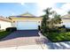 Charming single-story home with a red brick driveway, a two-car garage and lush landscaping at 16106 Amethyst Key Dr, Wimauma, FL 33598