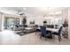 Open concept living room with a comfortable sectional, dining table with blue chairs, and tiled floors at 16106 Amethyst Key Dr, Wimauma, FL 33598