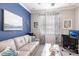 Bright and airy home office with a blue accent wall, a white sofa, and a computer desk at 16106 Amethyst Key Dr, Wimauma, FL 33598