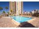 Bright pool area with lounge seating and umbrellas with multiple buildings in the background at 1621 Gulf Blvd # 308, Clearwater Beach, FL 33767