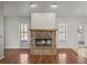 Close-up shot of the living room's brick fireplace with wood mantle, flanked by windows and views of the screened-in lanai at 18253 Townsend House Rd, Dade City, FL 33523