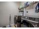 A modern laundry room with front loading machines and convenient storage solutions on the shelving at 20220 Autumn Fern Ave, Tampa, FL 33647