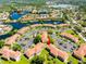 Aerial view of a community featuring multiple buildings, parking lots, ponds, and lush landscaping, plus lake views beyond at 21011 Picasso Ct # 101, Land O Lakes, FL 34637