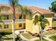 Charming multi-story condo building featuring a vibrant yellow exterior, balconies, and lush palm trees in a well-manicured landscape at 21011 Picasso Ct # 101, Land O Lakes, FL 34637