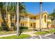 Charming multi-story condo building featuring a vibrant yellow exterior, balconies, and lush palm trees in a well-manicured landscape at 21011 Picasso Ct # 101, Land O Lakes, FL 34637