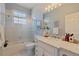 Well-lit bathroom with white tiles, glass shower door, marble countertop, and decorative artwork at 218 Sand Key Estates Dr, Clearwater Beach, FL 33767
