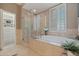 Bright bathroom featuring a soaking tub, glass shower, and access to a walk-in closet at 218 Sand Key Estates Dr, Clearwater Beach, FL 33767