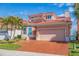 Beautiful home with a brick driveway, two-car garage, red tile roof, and lush tropical landscaping at 218 Sand Key Estates Dr, Clearwater Beach, FL 33767