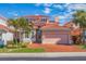 Mediterranean-style home showcasing a red tile roof, two-car garage, and lush tropical landscaping at 218 Sand Key Estates Dr, Clearwater Beach, FL 33767