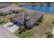 Aerial view of home with lush landscaping, pond view, and three-car garage at 2234 Nottingham Greens Dr # 2234, Sun City Center, FL 33573