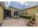 Relaxing outdoor patio features brick flooring, an umbrella-covered table, chair seating, views of the lush, green yard, and a screened-in lanai at 2286 Sifield Greens Way # 2286, Sun City Center, FL 33573