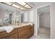 Bathroom featuring a well-lit vanity with dual sinks, light wood cabinets, and a view to another room at 2462 Indian E Trl, Palm Harbor, FL 34683