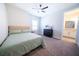 Bedroom with a ceiling fan, large window, a bed with a light green comforter and a modern nightstand and dresser at 2671 Murray Pass, Odessa, FL 33556