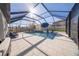 Screened-in pool with blue patio furniture, sunshade umbrella, and a tiled deck is ideal for entertaining at 2671 Murray Pass, Odessa, FL 33556