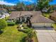 Expansive home featuring a well-manicured lawn, lush landscaping, and a three-car garage, blending luxury with curb appeal at 2806 Forest Club Dr, Plant City, FL 33566